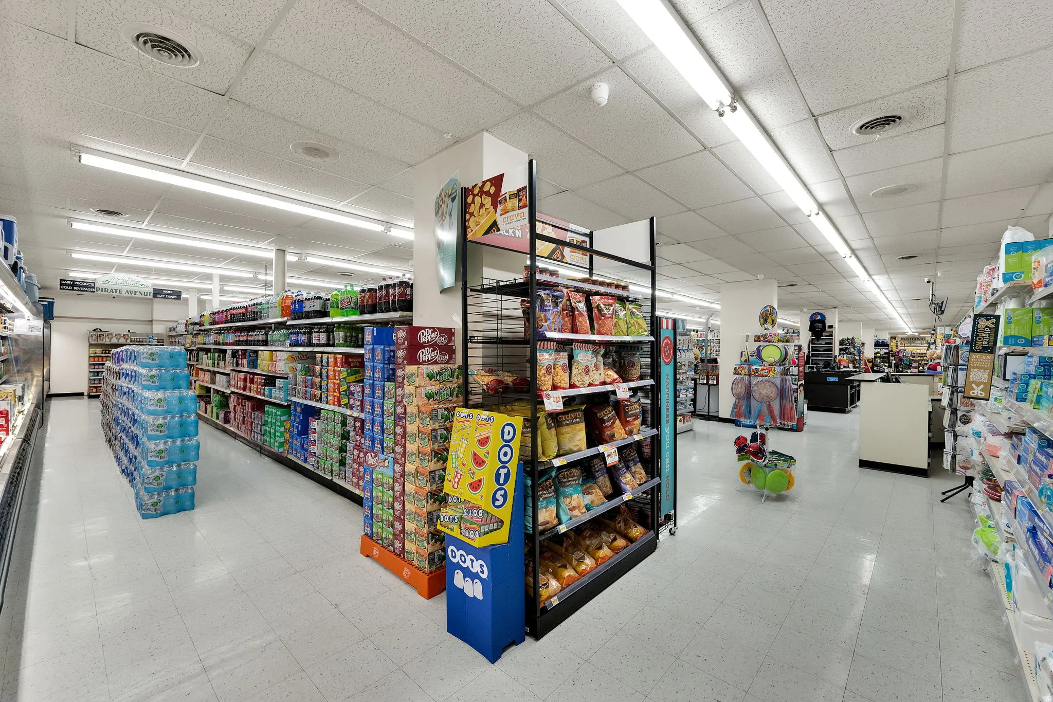 Spacious retail interior featuring fluorescent lighting, white ceiling tiles, and white vinyl flooring