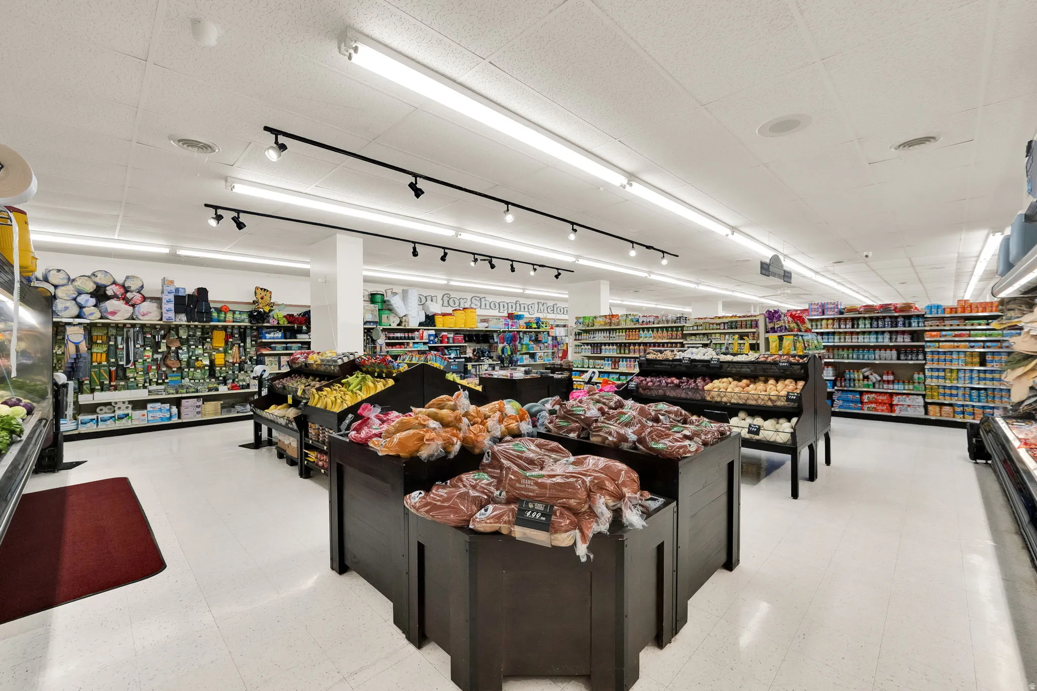 Spacious retail interior featuring white floor tiles and extensive overhead lighting