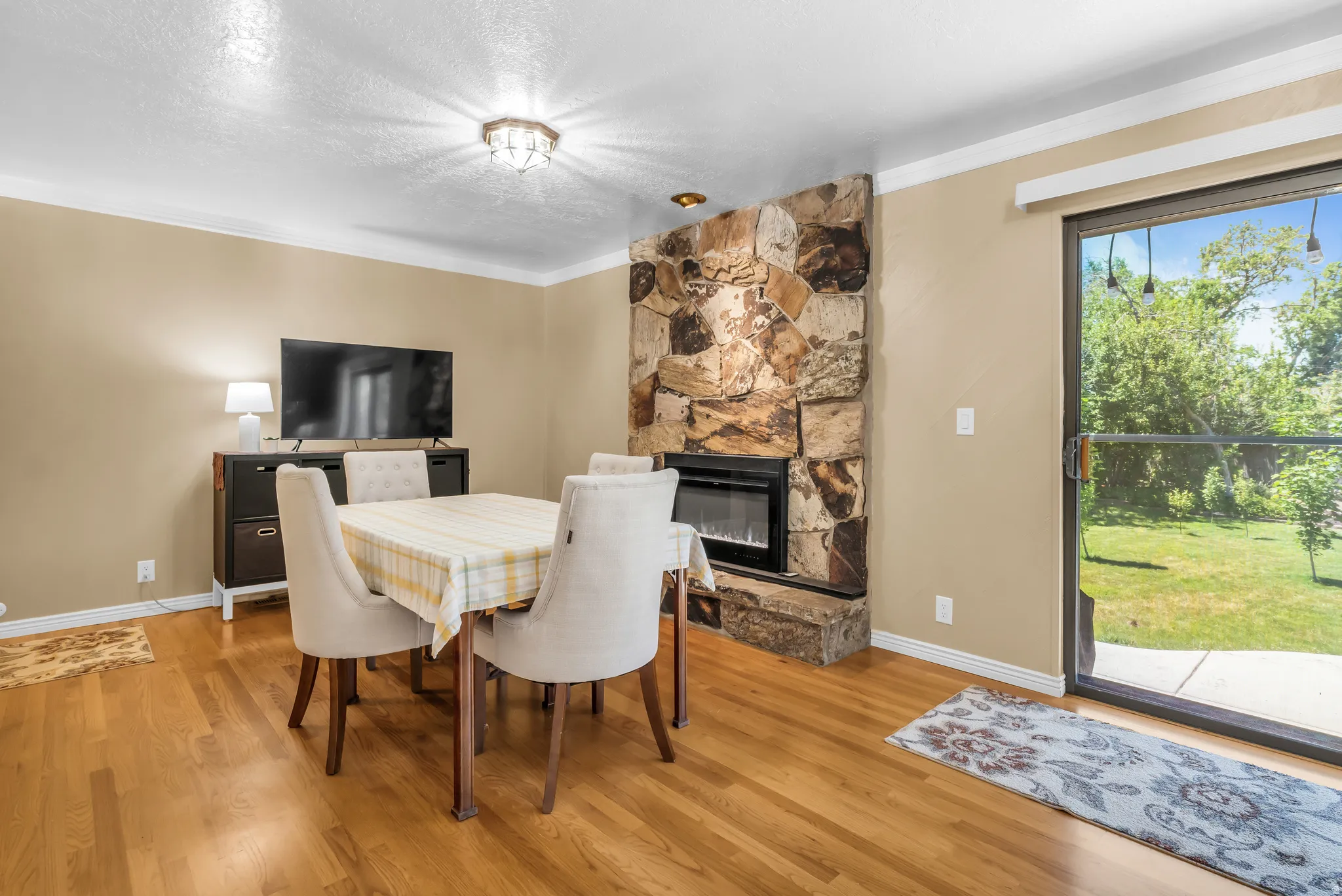 Hardwood-style flooring throughout this dining area featuring a stone-clad fireplace with an electric insert