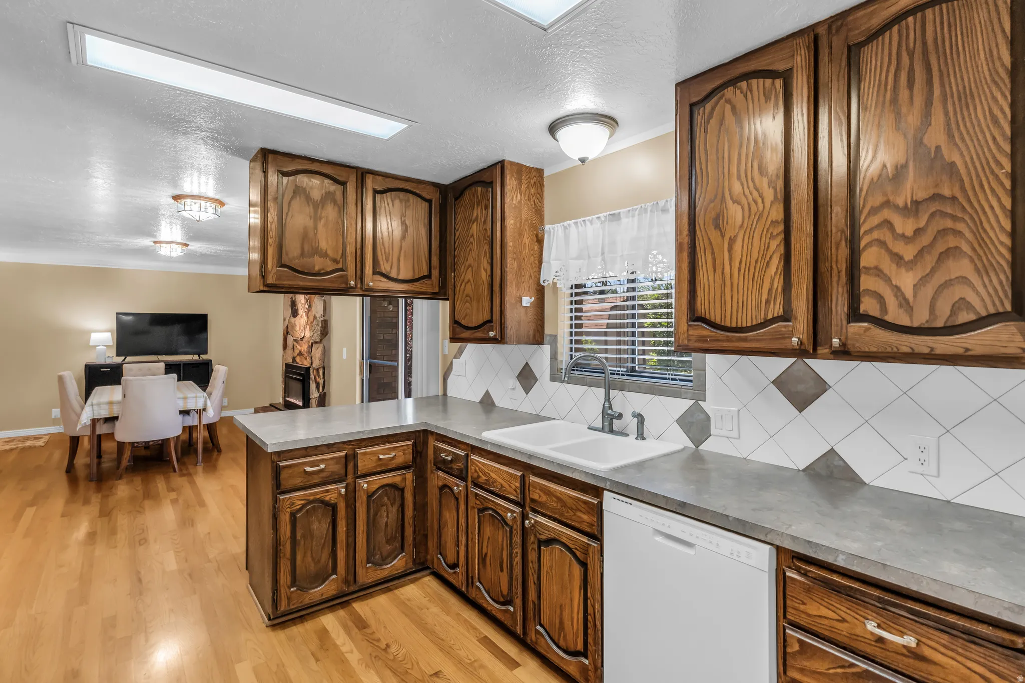 U-shaped kitchen featuring wood cabinetry, a double basin sink, and a tiled backsplash