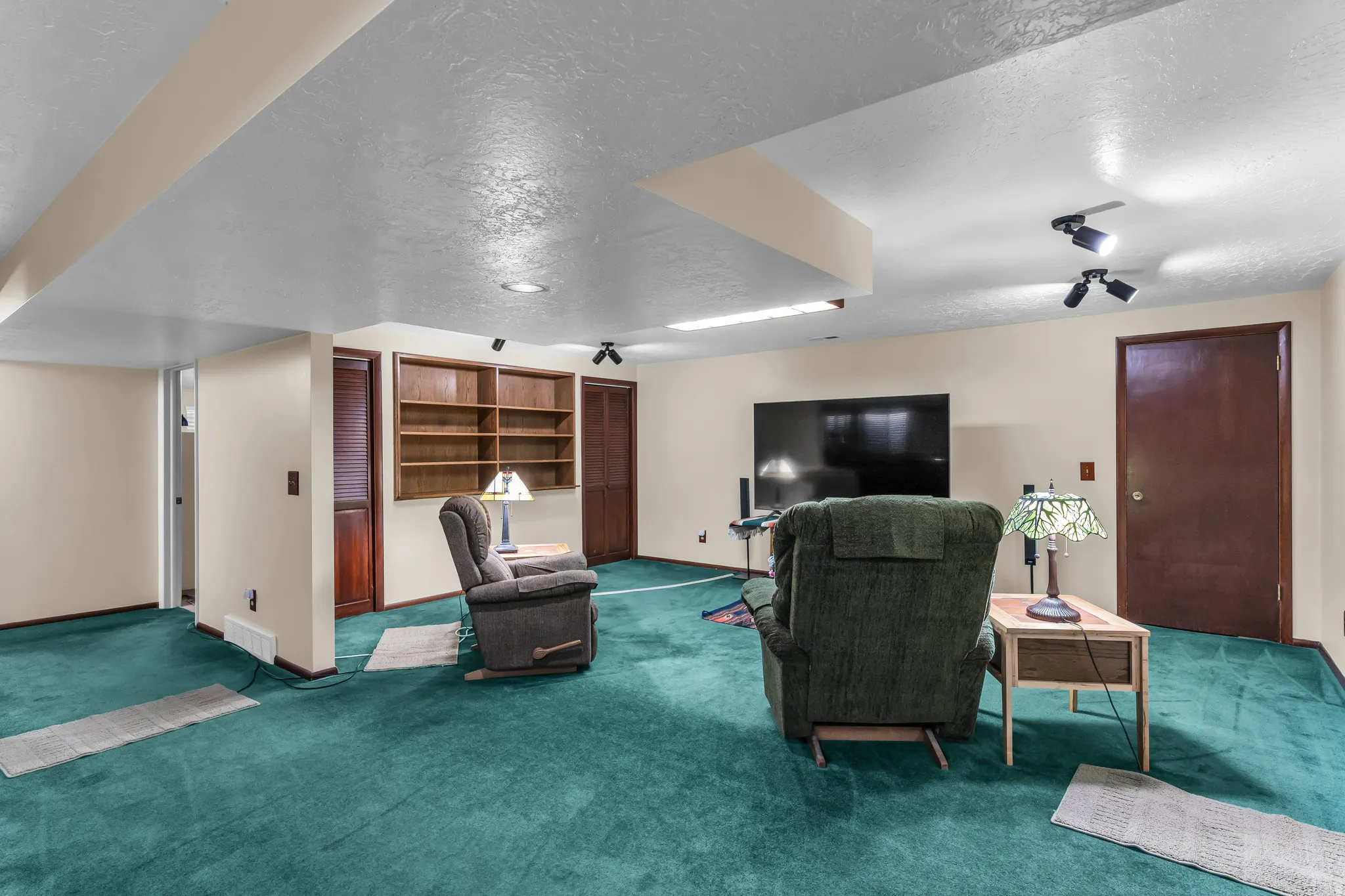 Spacious room featuring plush carpeting, recessed lighting, track lighting, and built-in shelving