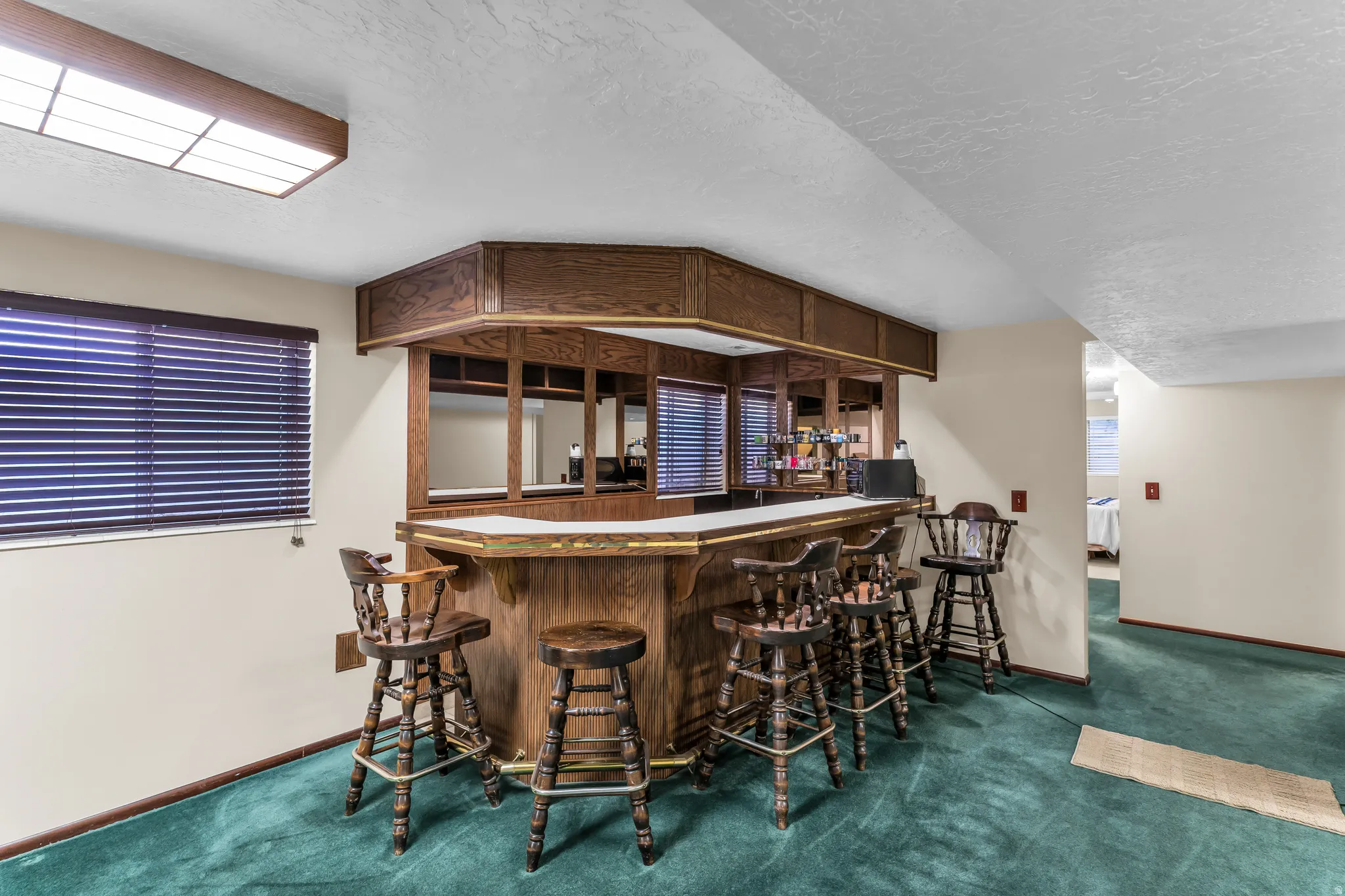 Built-in wood-finish bar featuring an overhead cabinet, mirrored backsplash, and countertop space