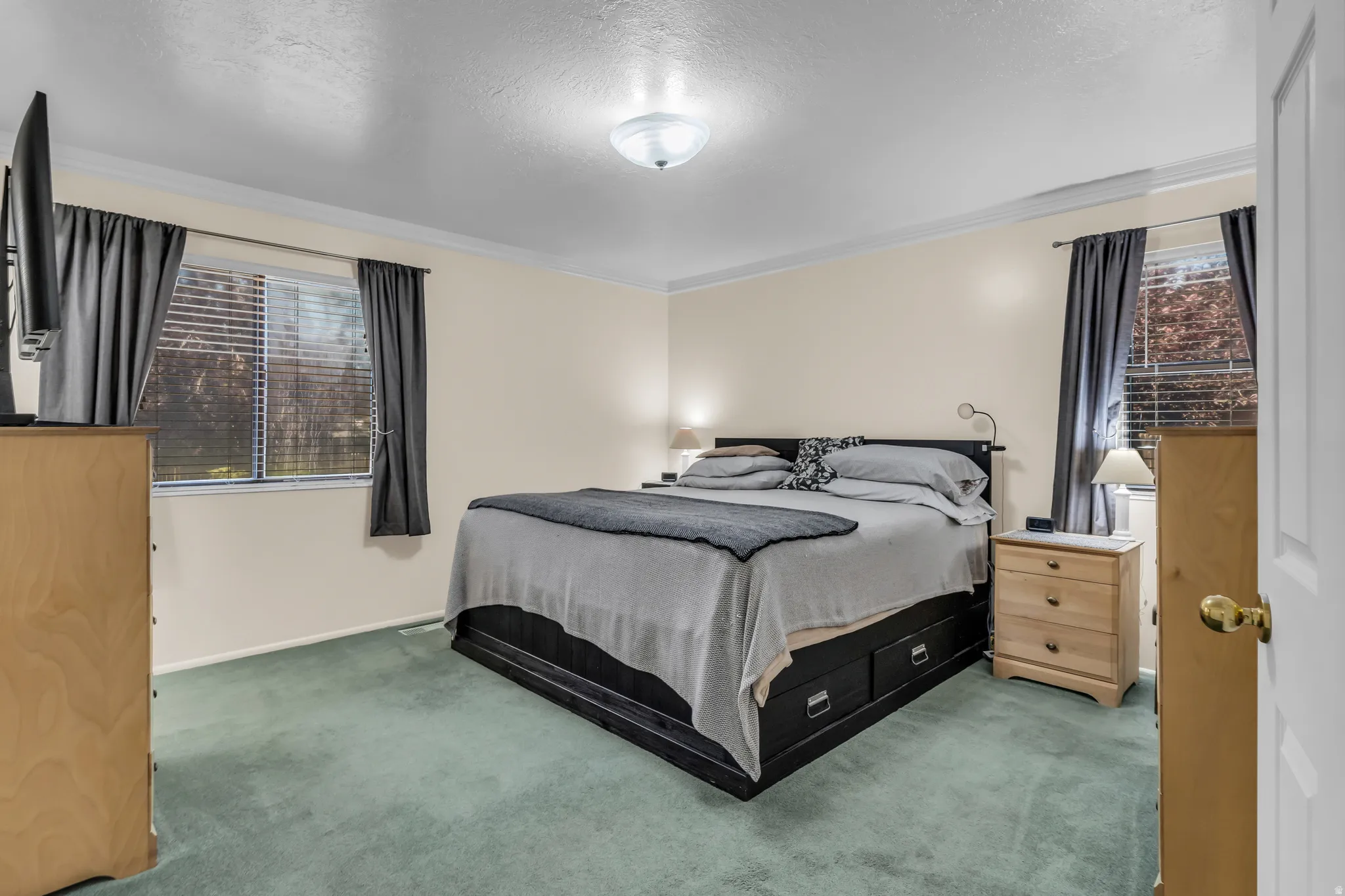 Carpeted bedroom with neutral-toned walls, a single window, and crown molding