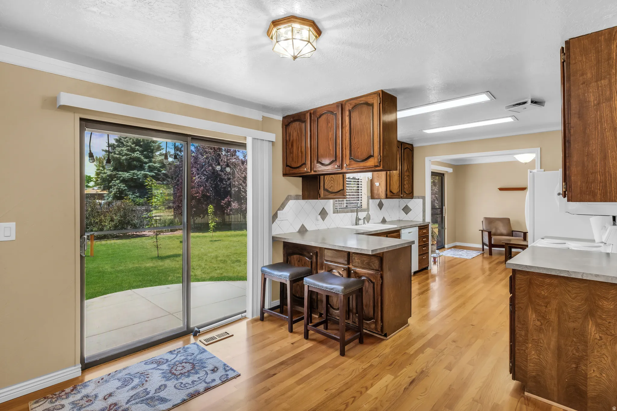 Kitchen featuring wood-finish flooring, rich wood cabinetry, light-toned countertops, and a tile backsplash
