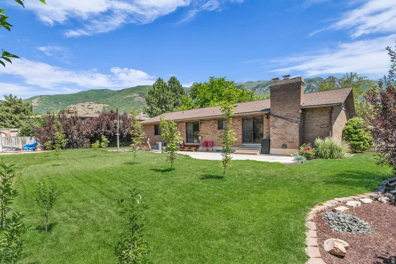 Expansive green lawn with mature landscaping and a brick-built chimney