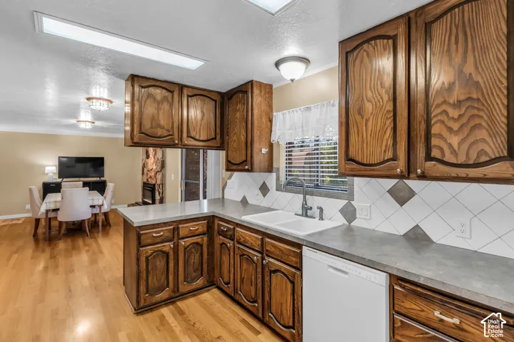 U-shaped kitchen featuring wood cabinetry, a double basin sink, and a tiled backsplash