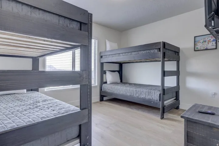Room featuring two dark wood-finish bunk beds, light wood-finish flooring, and white walls