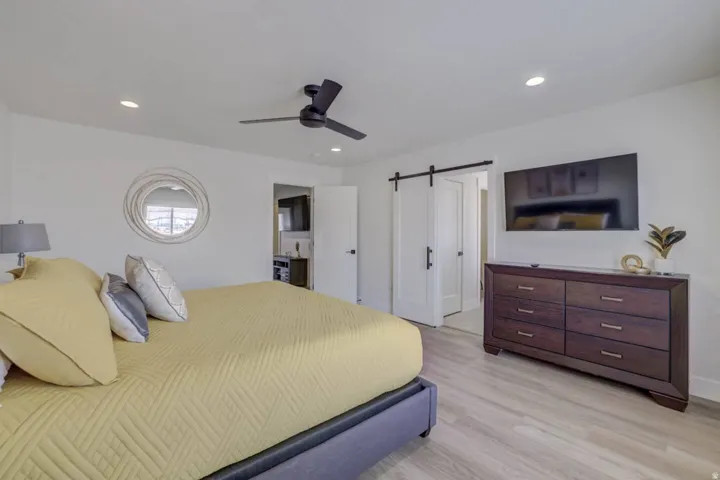 Light-toned wood-finish flooring, recessed lighting, and a dark-toned ceiling fan