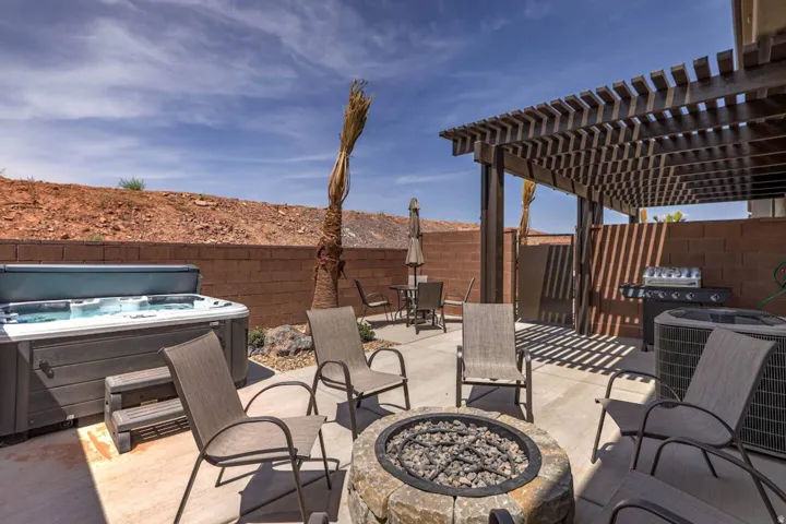 Expansive outdoor patio featuring a hot tub, stone fire pit, built-in BBQ, and a large pergola