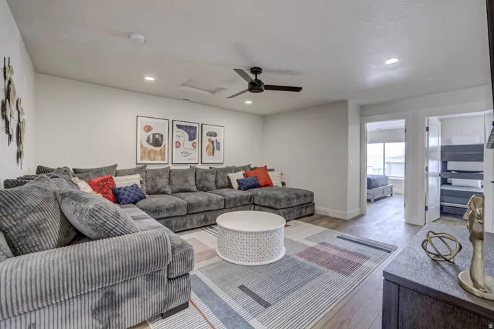 Spacious room featuring wood-finish flooring, recessed lighting, and a contemporary ceiling fan