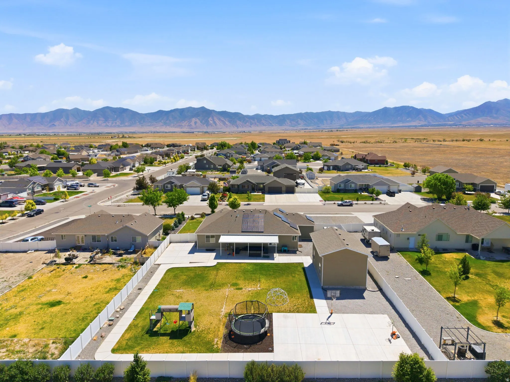 Expansive residential property featuring a large concrete patio, a dedicated sports court with a basketball hoop, and a separate detached garage structure