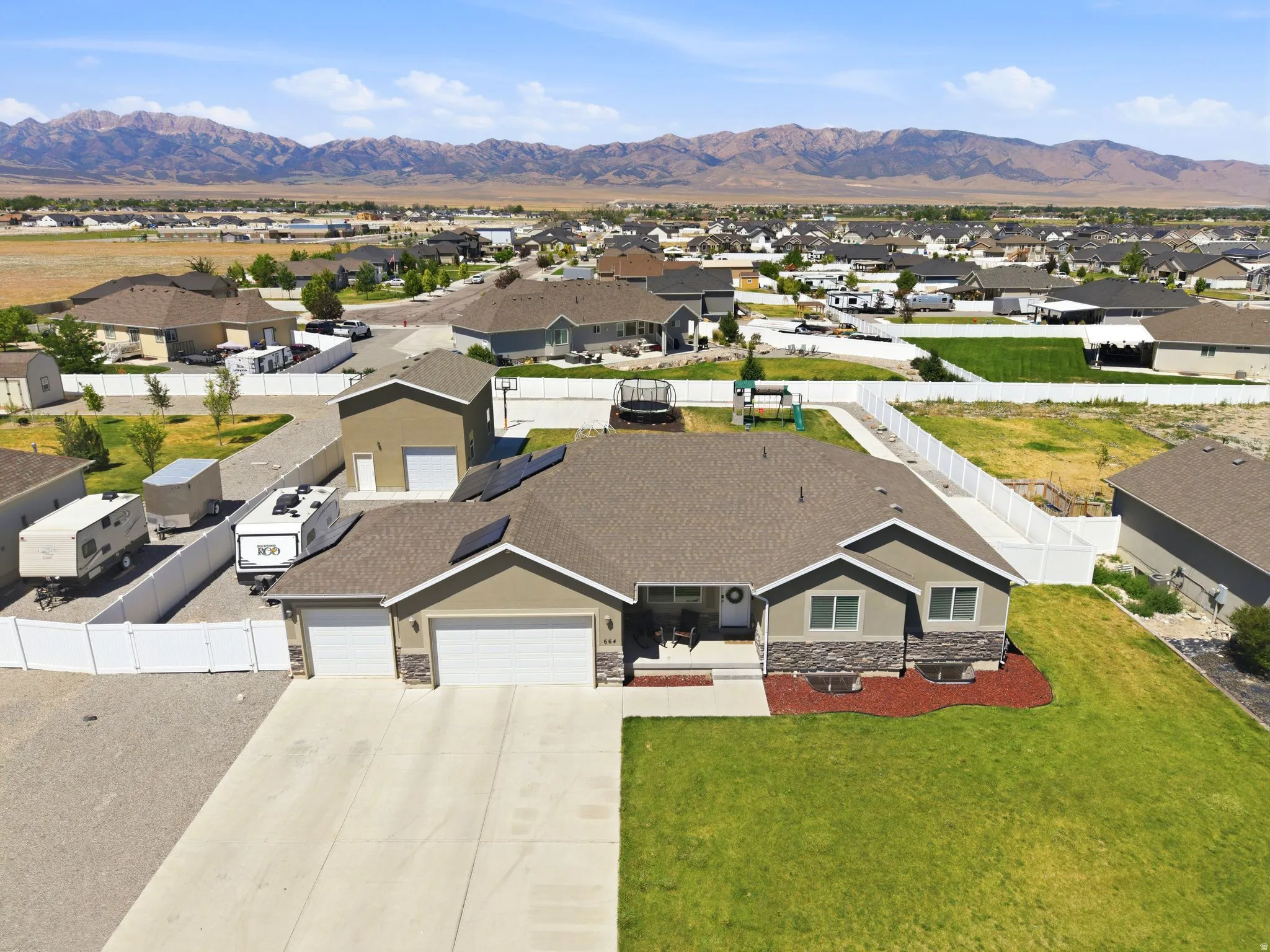 Single-story residence featuring a two-car garage, solar panels, and a concrete driveway