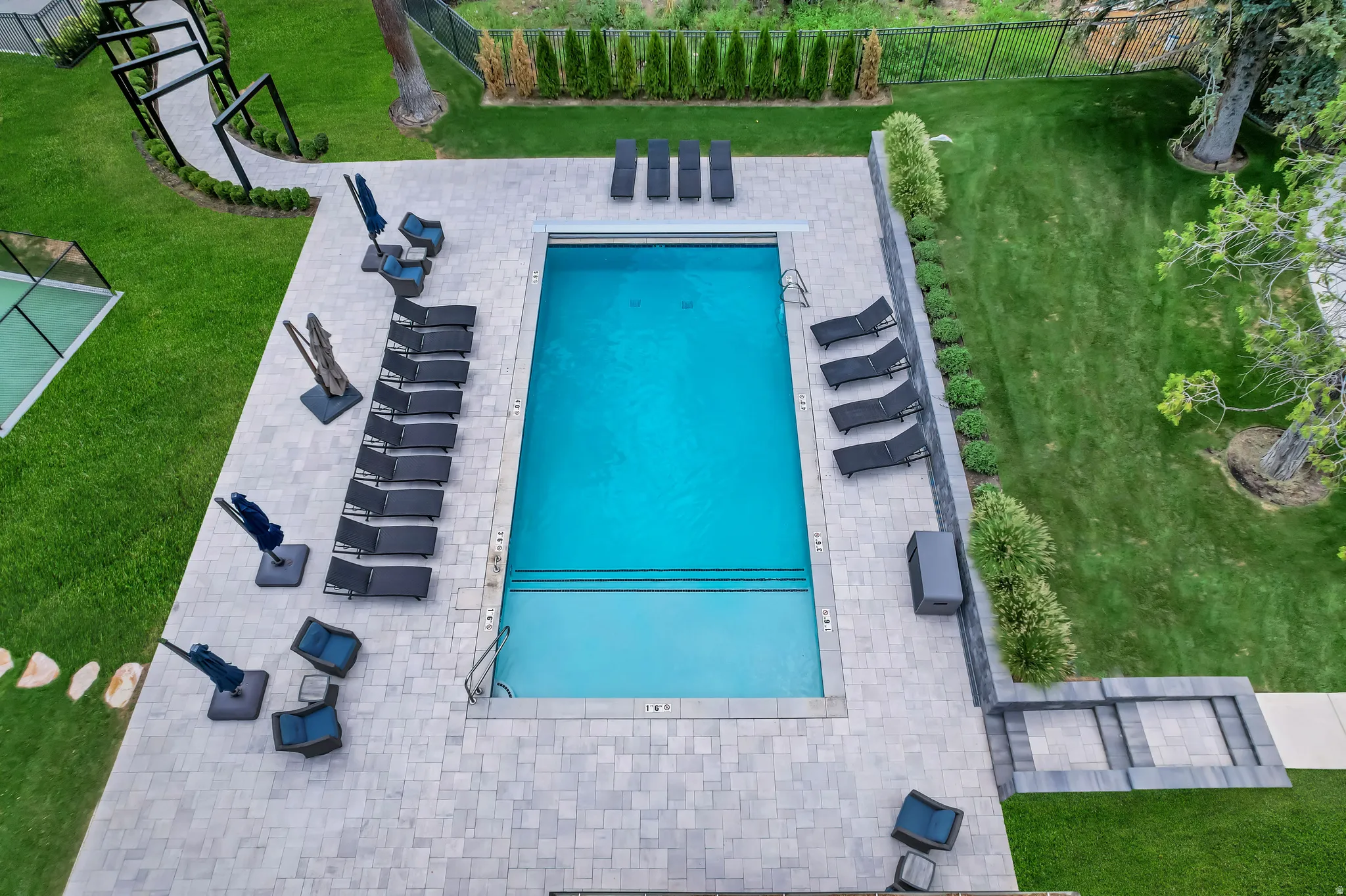 Rectangular swimming pool with integrated steps, surrounded by a light-toned paver patio