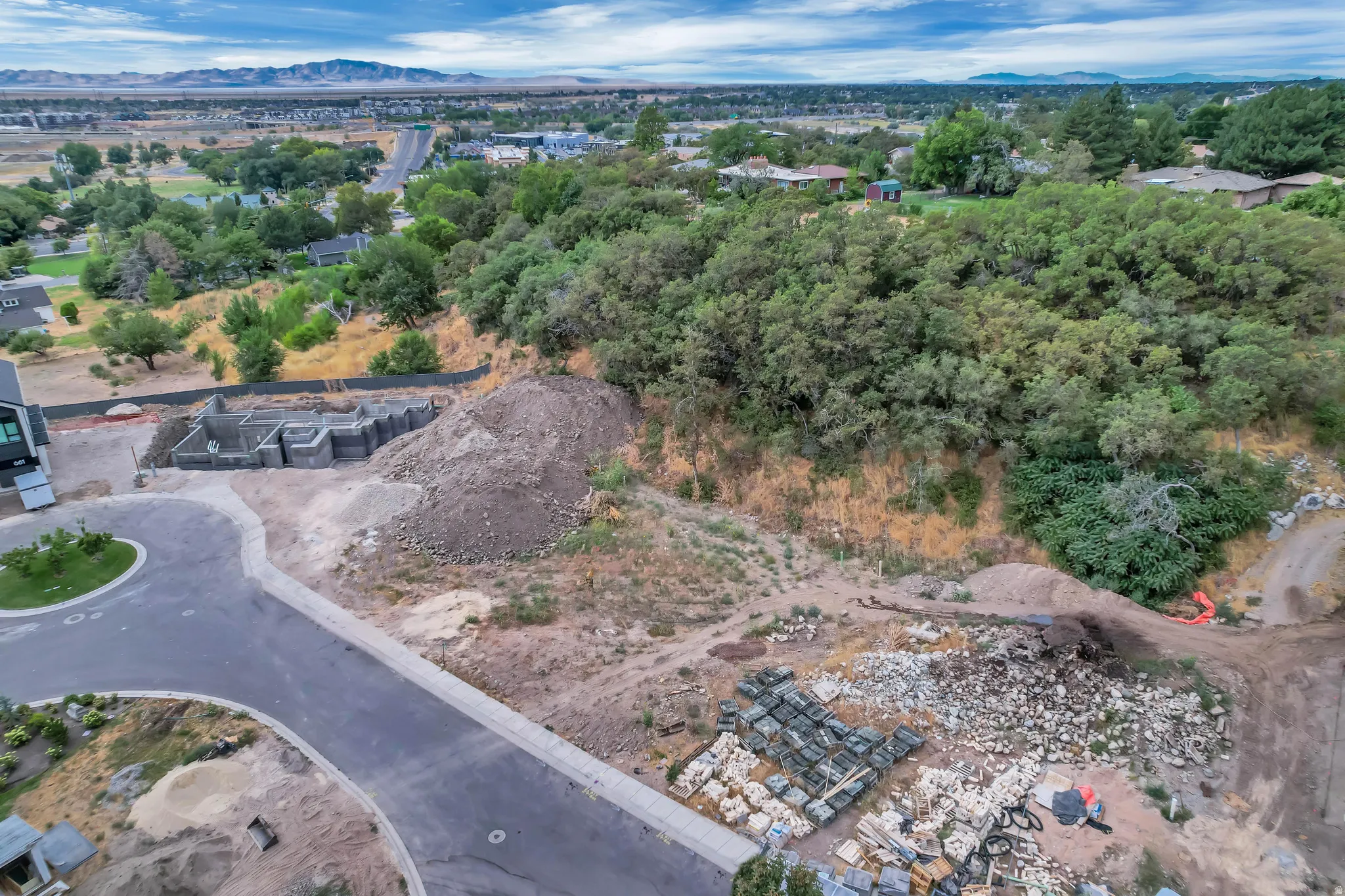 Partially developed hillside lot with visible foundation work and a paved cul-de-sac