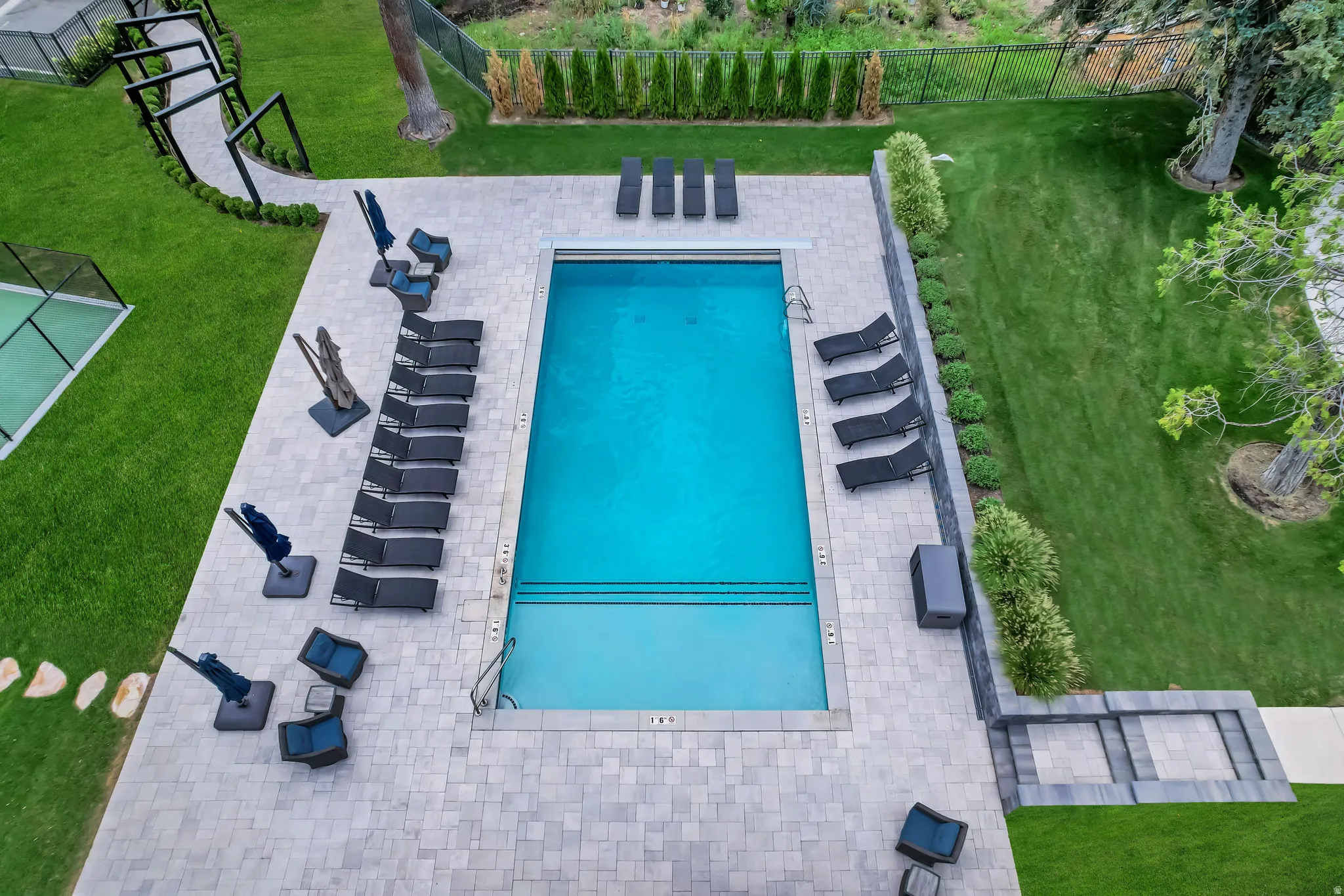 Rectangular swimming pool with integrated steps, surrounded by a light-toned paver patio
