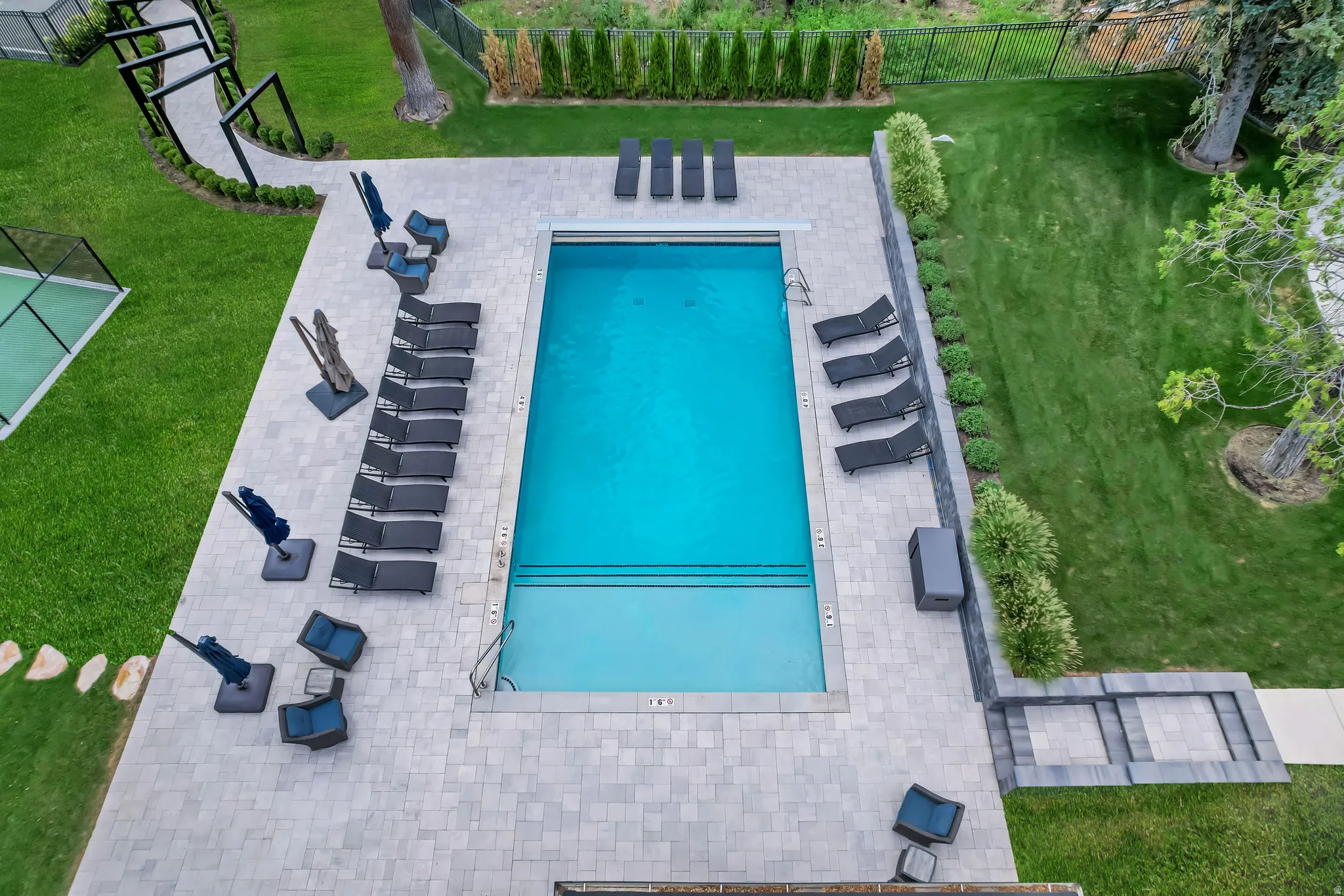 Rectangular swimming pool with integrated steps, surrounded by light-toned paver decking