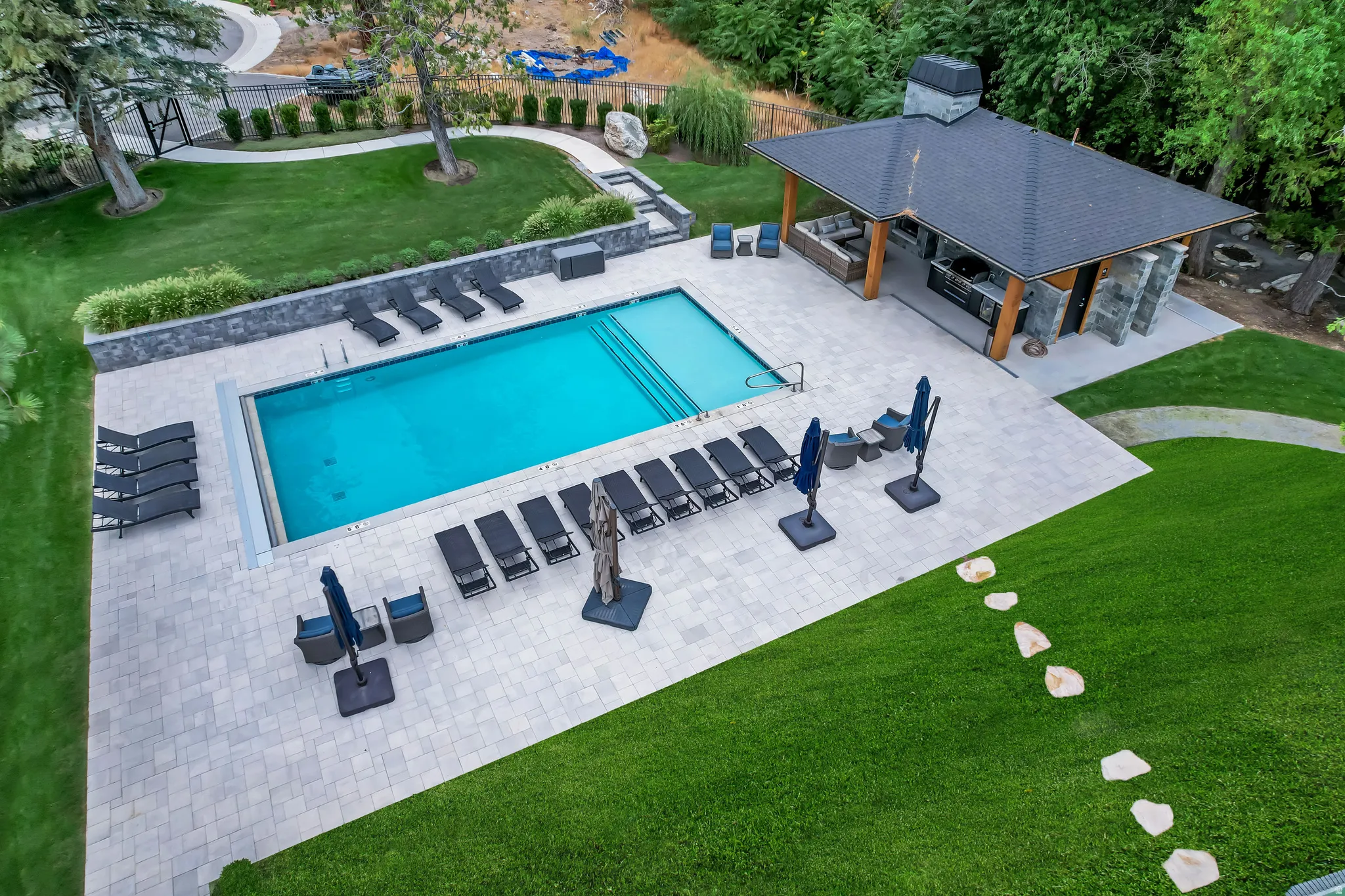 Outdoor living space featuring a rectangular swimming pool with integrated steps, surrounded by light-toned paver decking