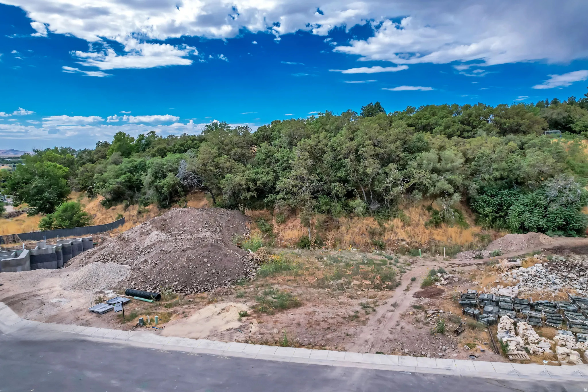 Graded lot featuring a concrete foundation structure, a large dirt mound, and a paved road frontage