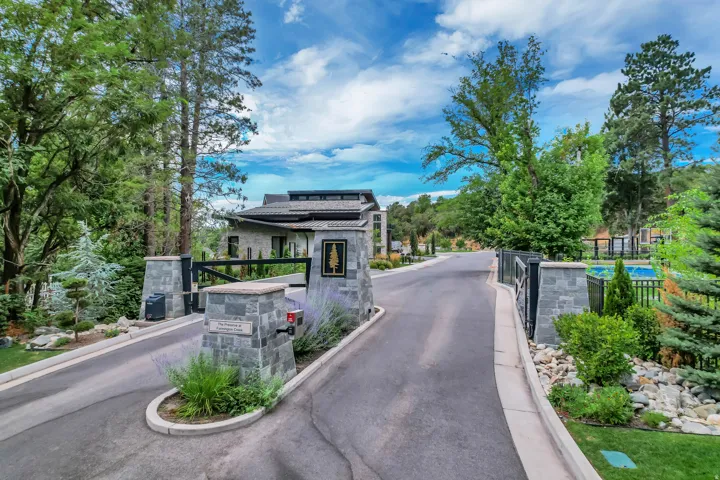 Stone-clad entrance with a modern architectural style, featuring an automated gate system