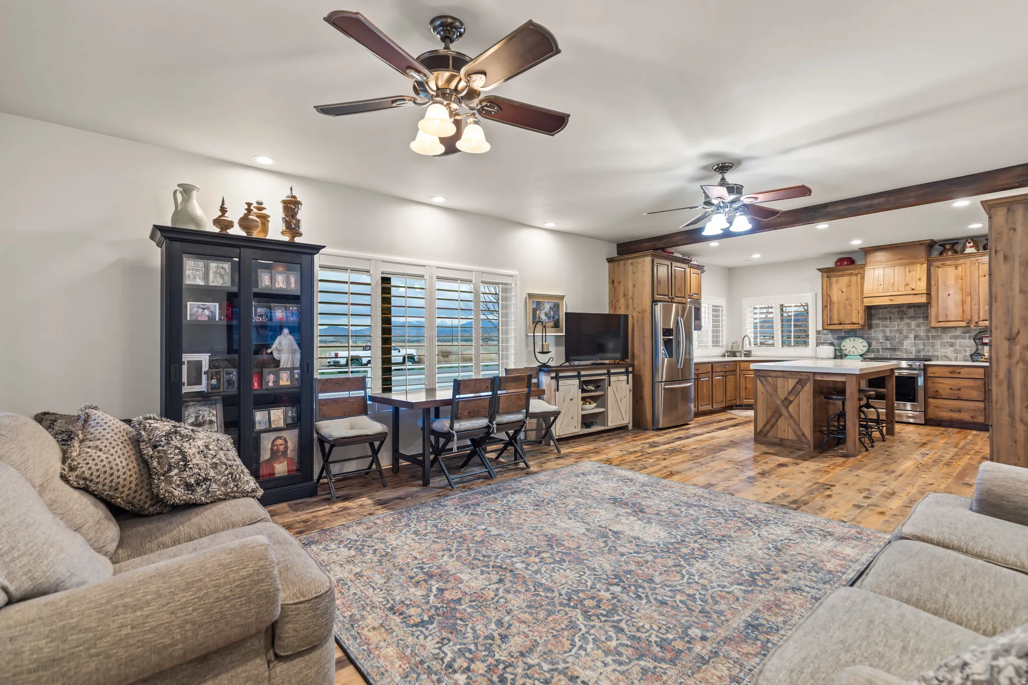 Open-concept living area with wood-finish flooring, recessed lighting, and ceiling fans