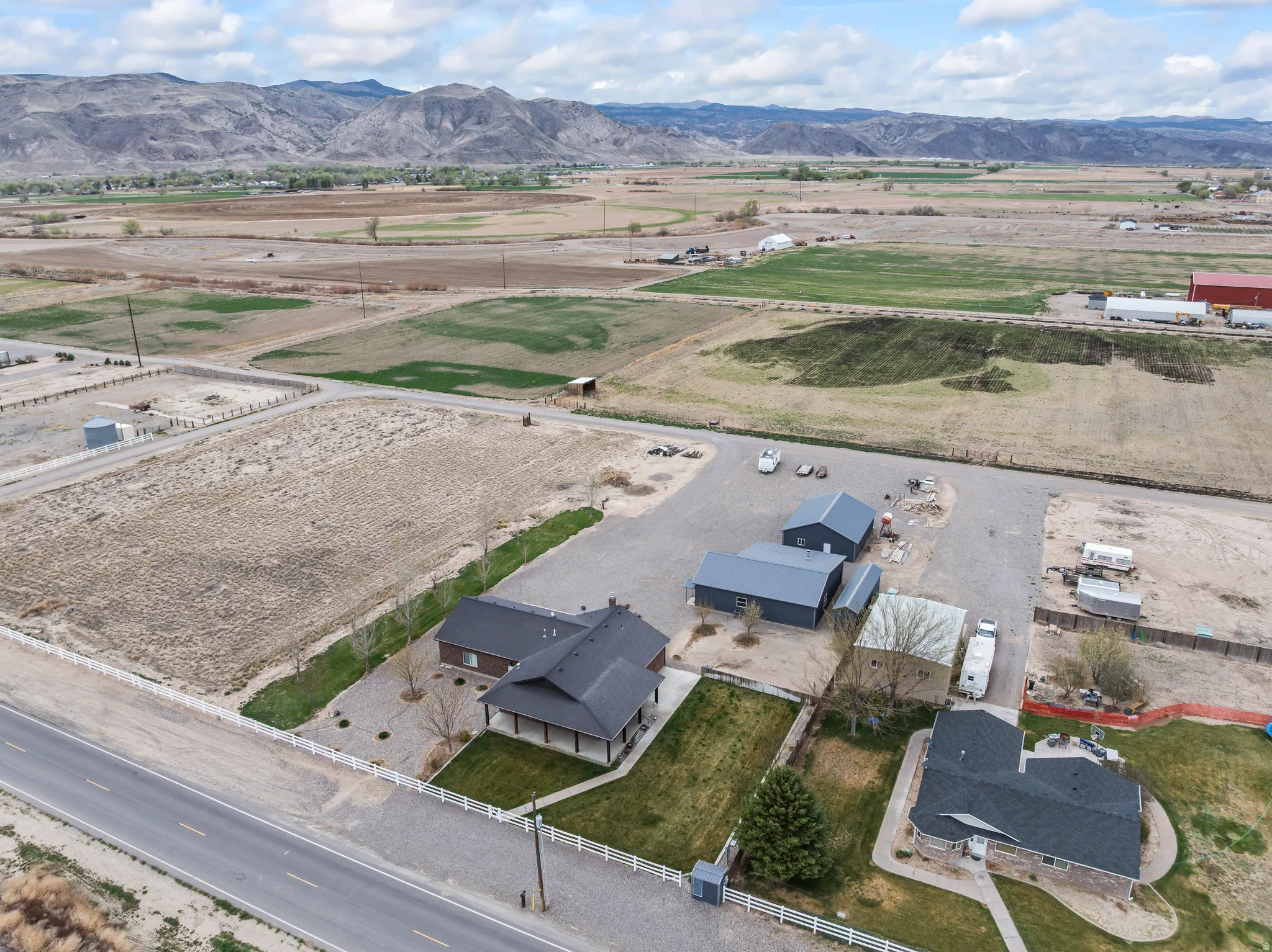 Property featuring multiple outbuildings, expansive paved areas, and a large fenced yard with established landscaping