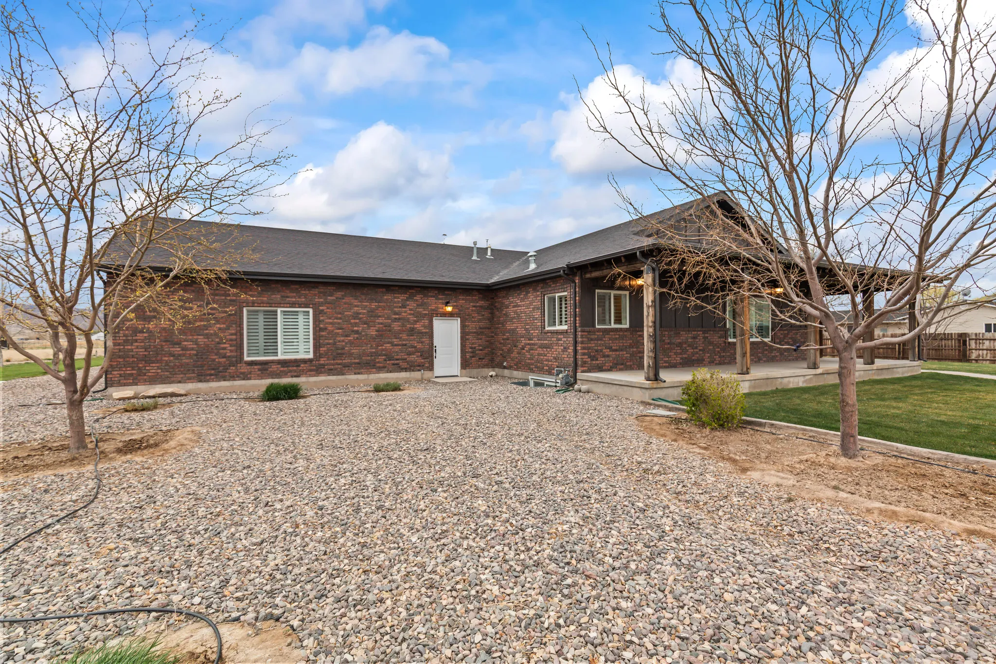 Brick exterior with a dark shingle roof and a covered porch featuring wood posts