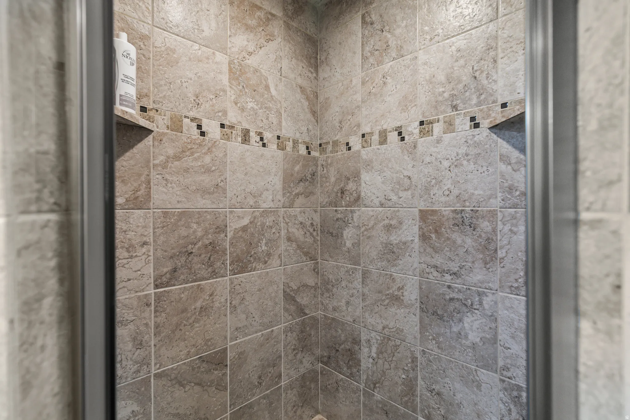 Tiled shower enclosure featuring a decorative mosaic border