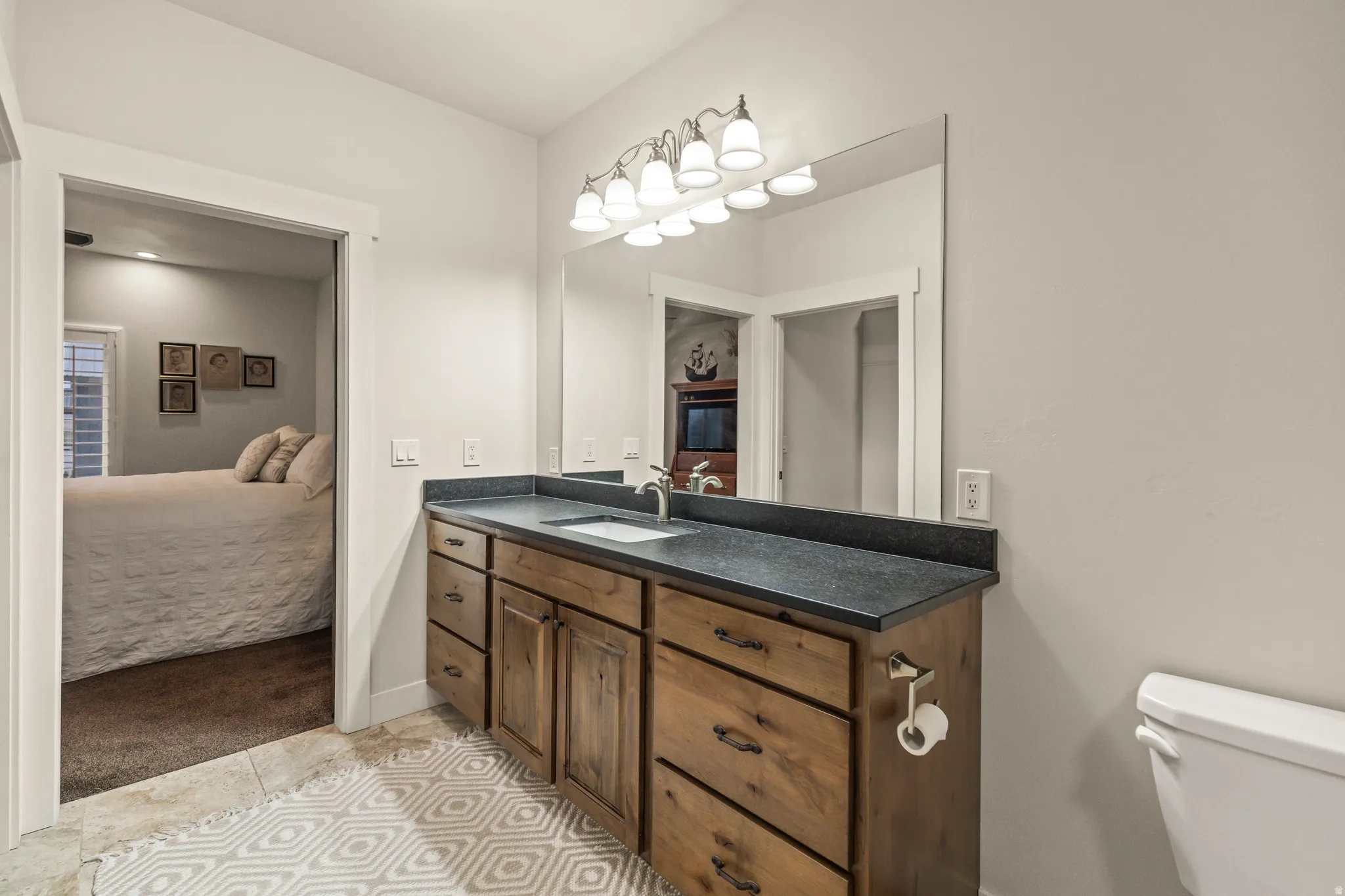 Bathroom vanity featuring a dark countertop, an undermount sink with a chrome faucet, and a large mirror