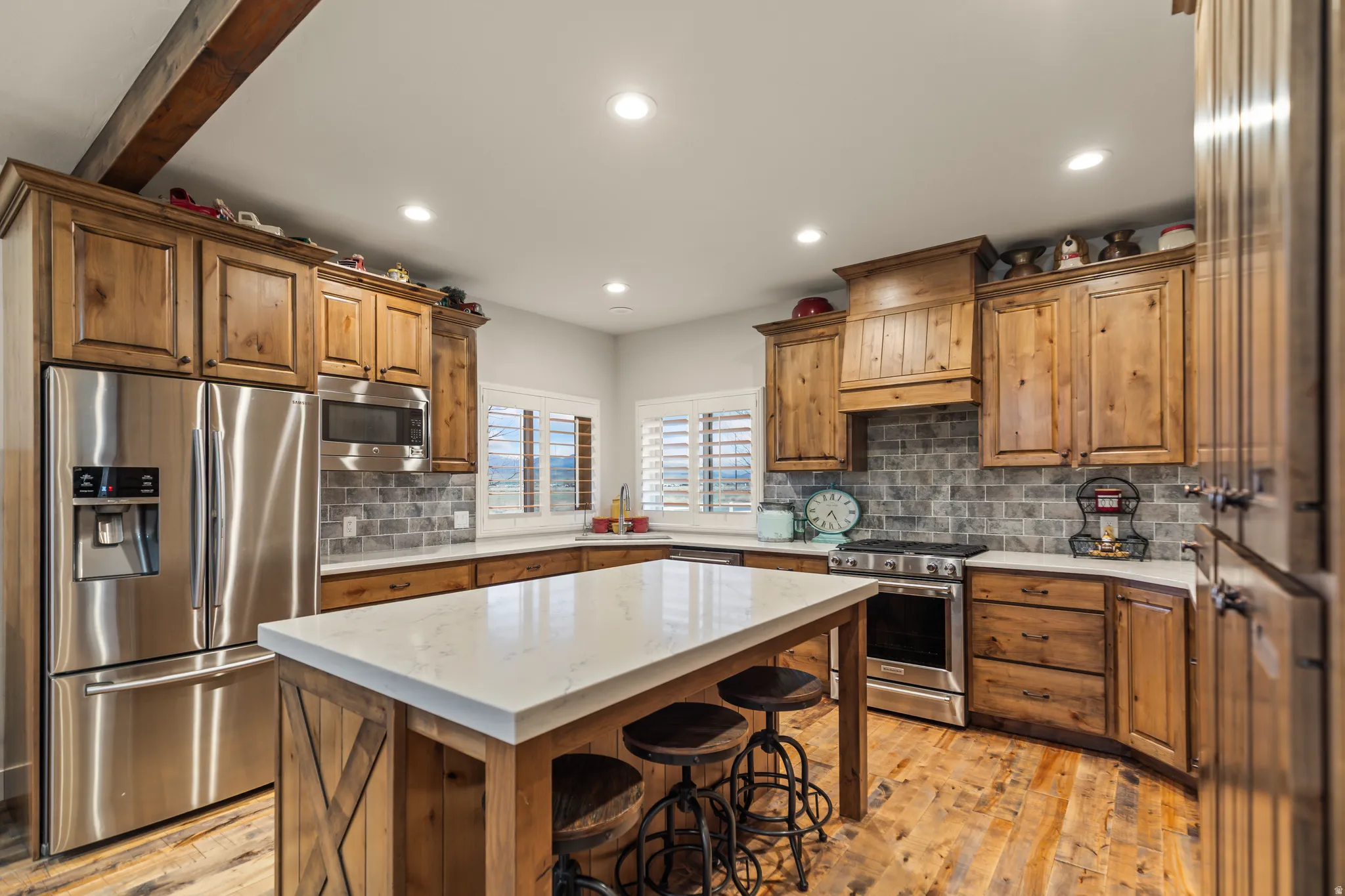 Kitchen featuring wood-finish cabinetry, stainless steel appliances, a white island countertop, and a gray tile backsplash