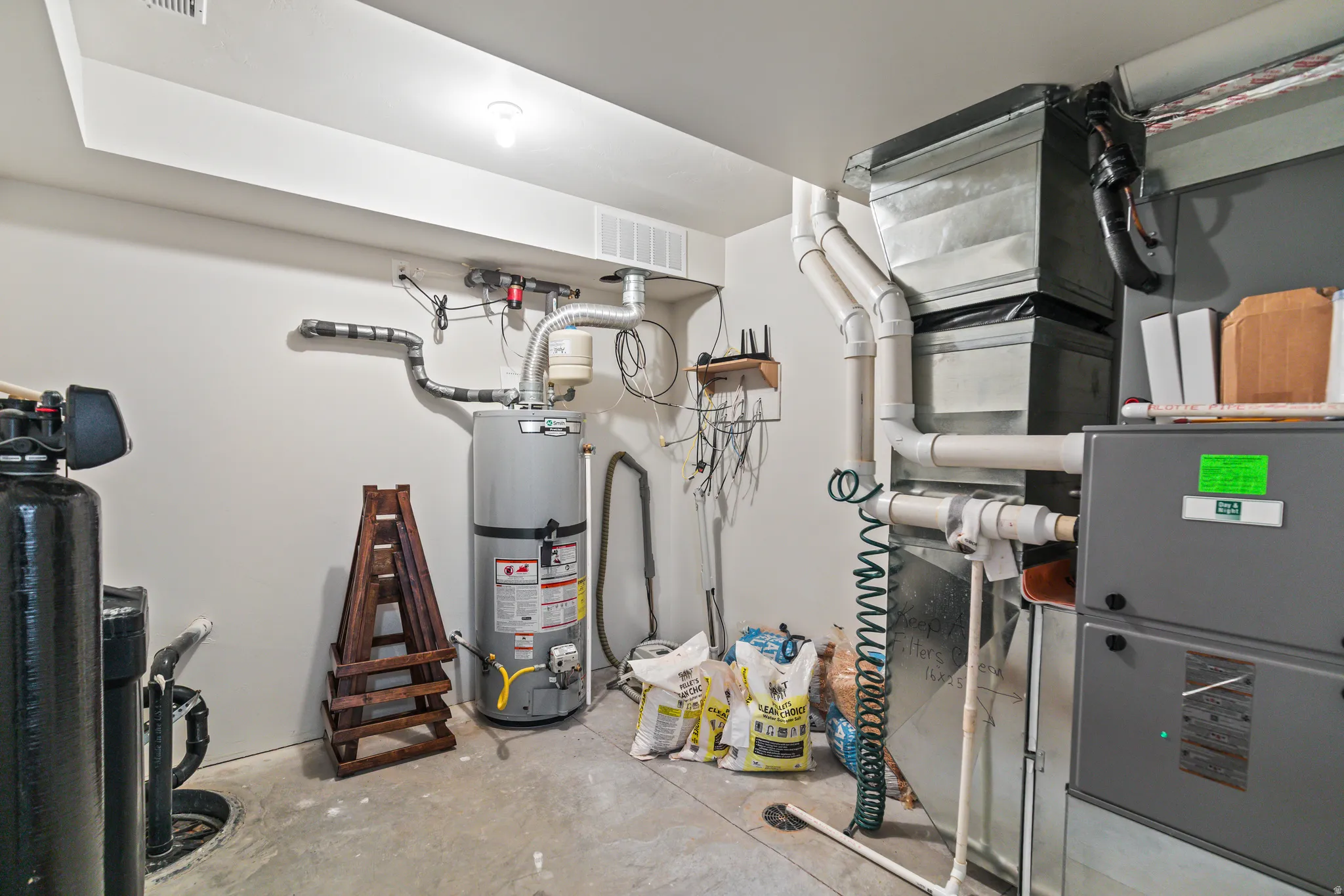 Utility room featuring a water heater, furnace, and water filtration system