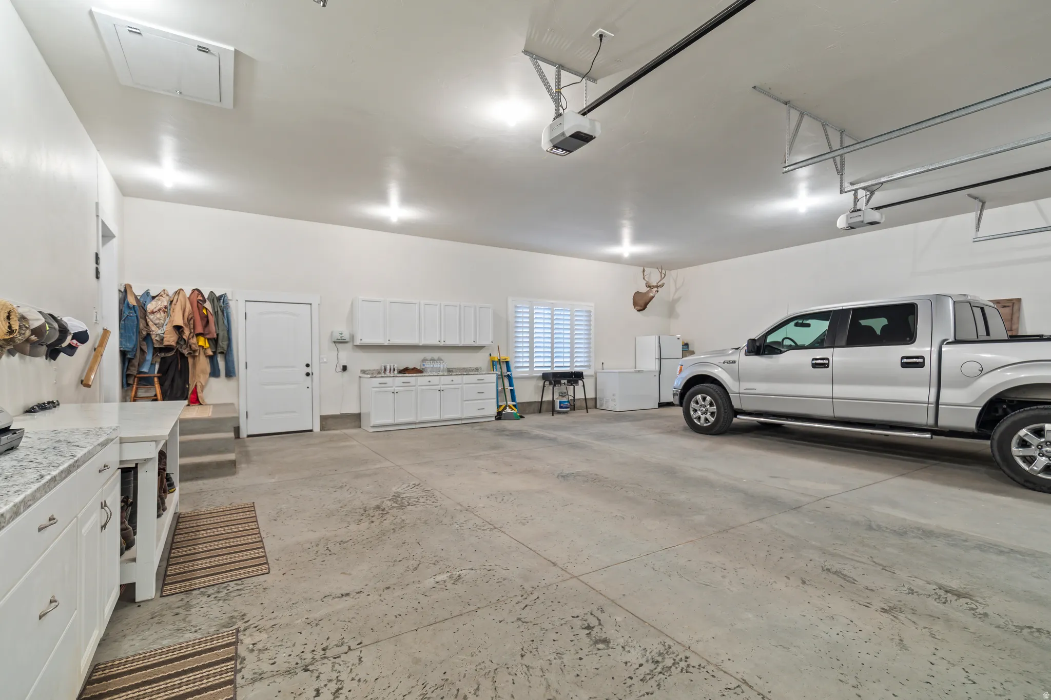 Spacious garage featuring high ceilings, multiple overhead lighting fixtures, and a concrete floor