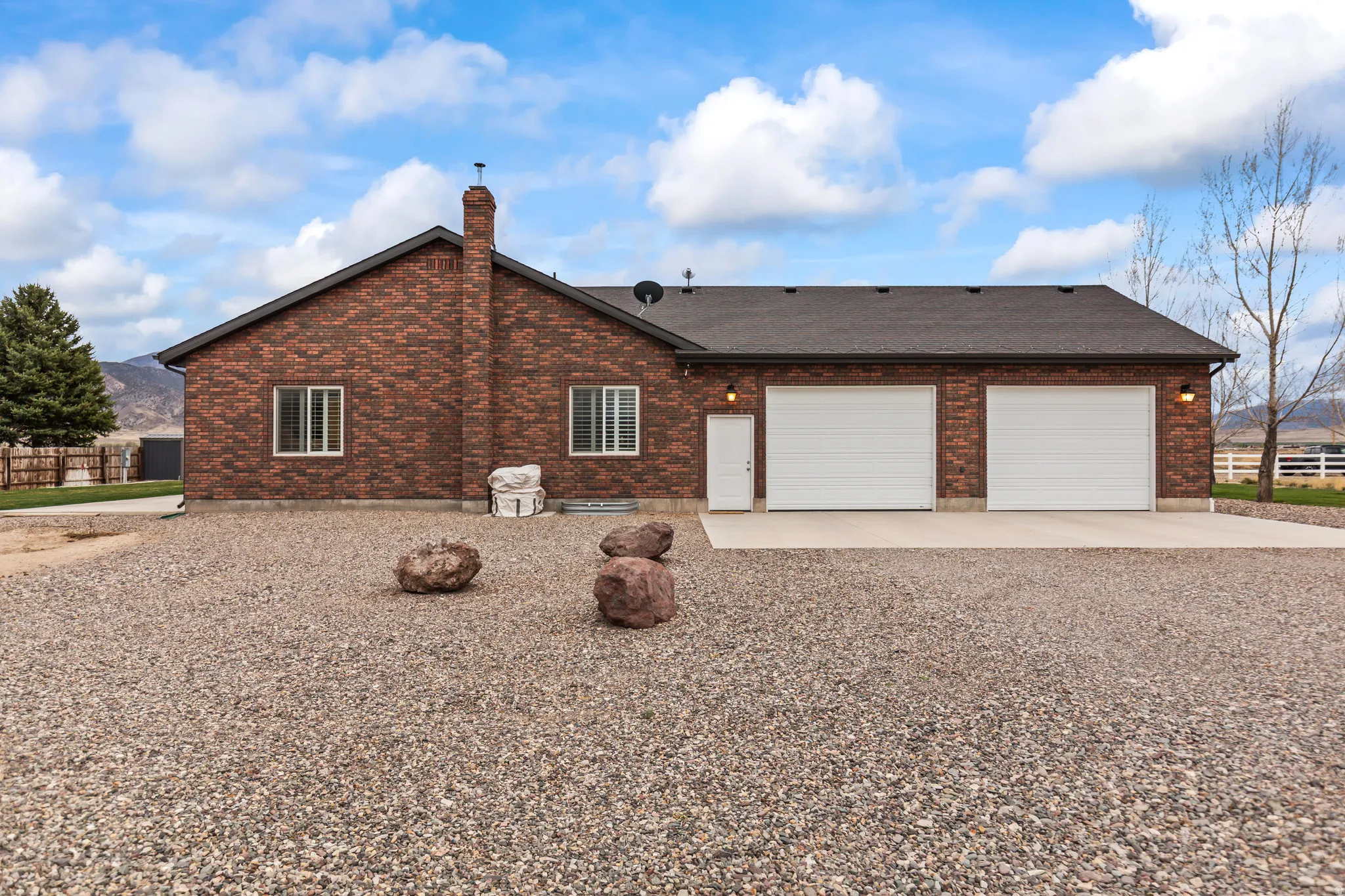 Red brick exterior featuring a multi-car garage with white doors, a white side access door, and exterior lighting fixtures