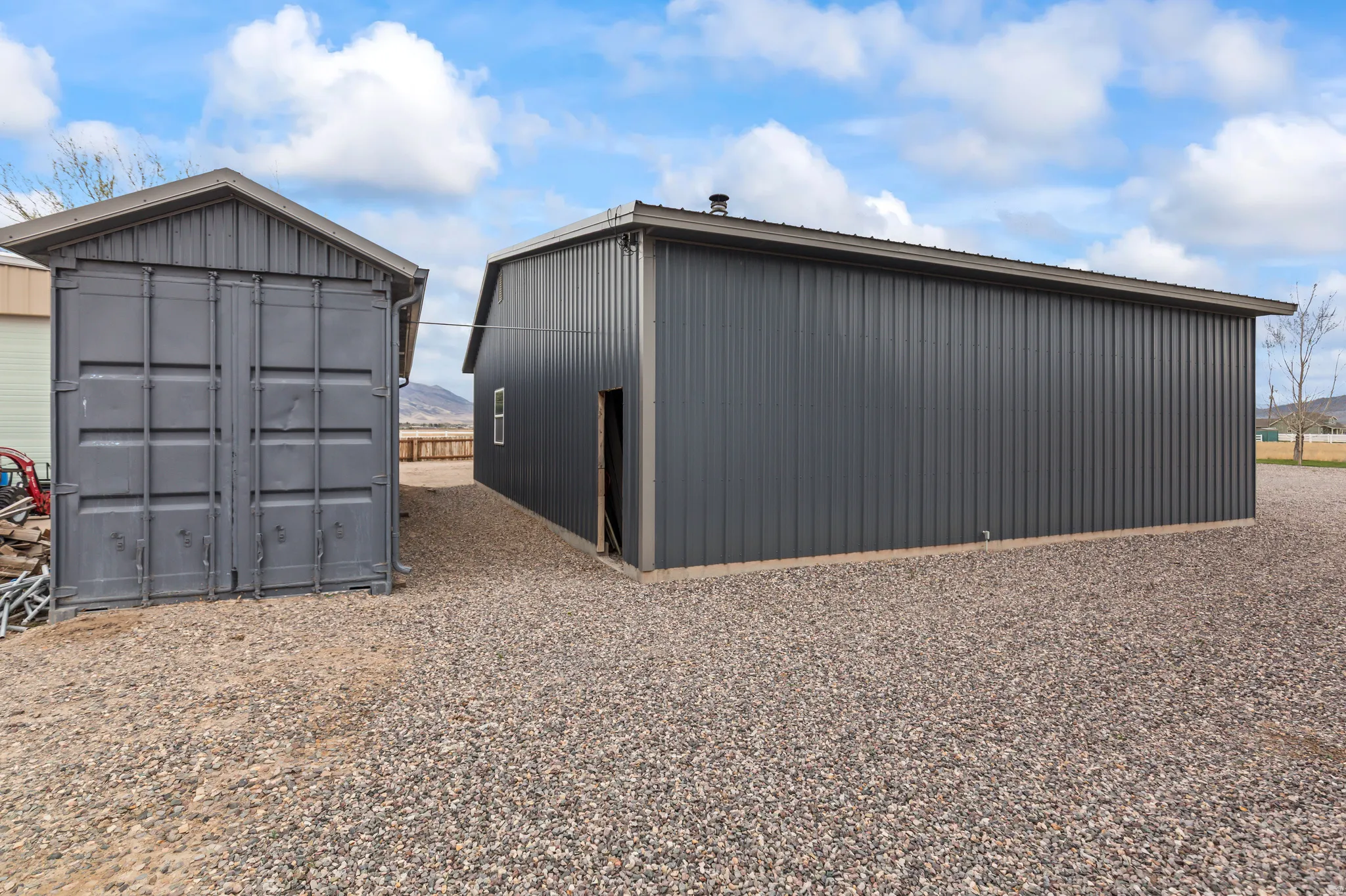 Two detached structures featuring corrugated metal siding and gravel ground cover