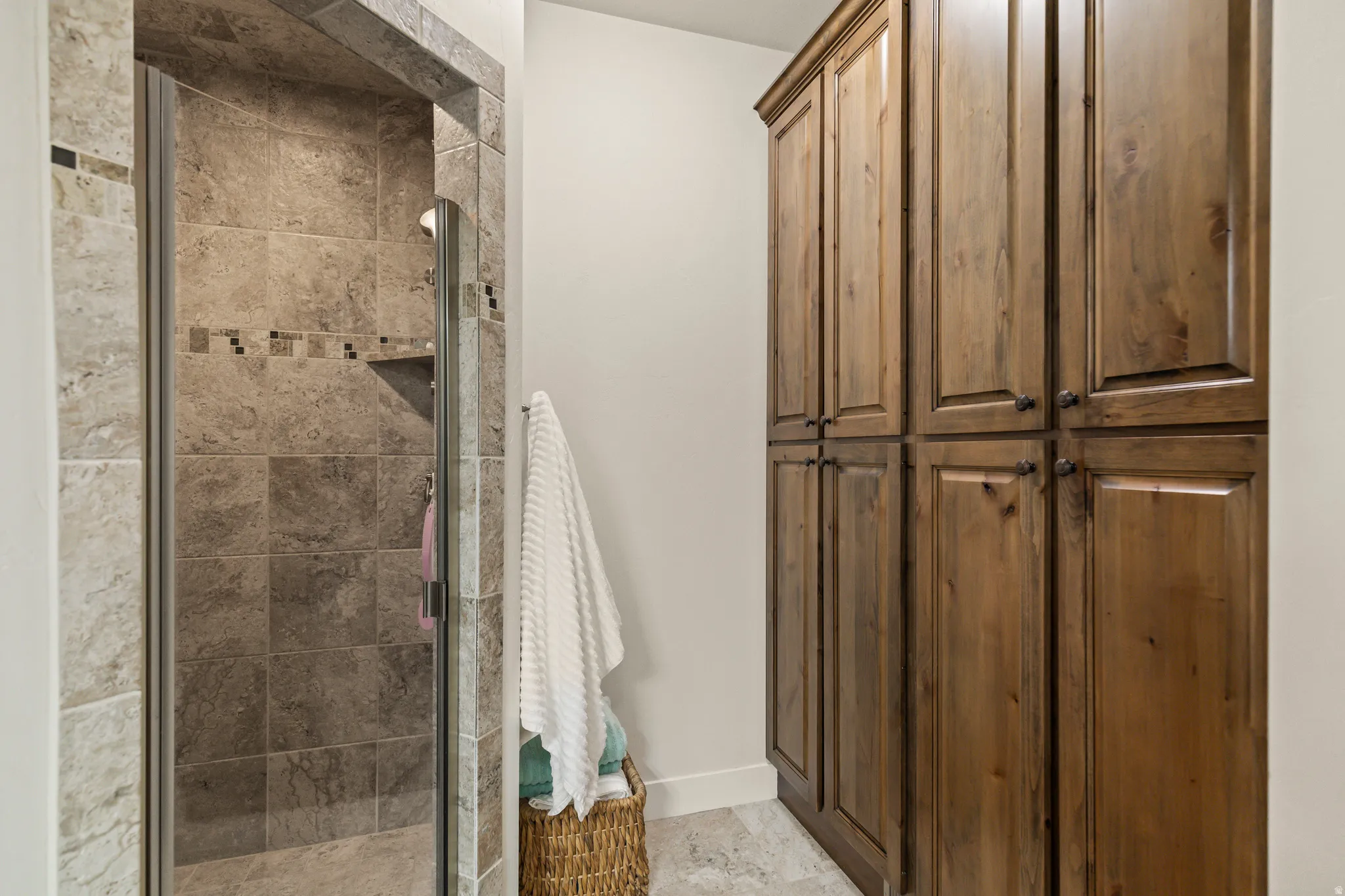 Tiled shower enclosure featuring a glass door and integrated shelf