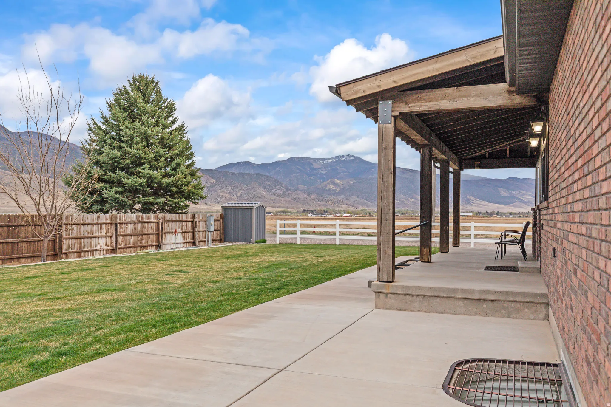 Expansive concrete patio with a covered porch featuring exposed wood beams and architectural lighting