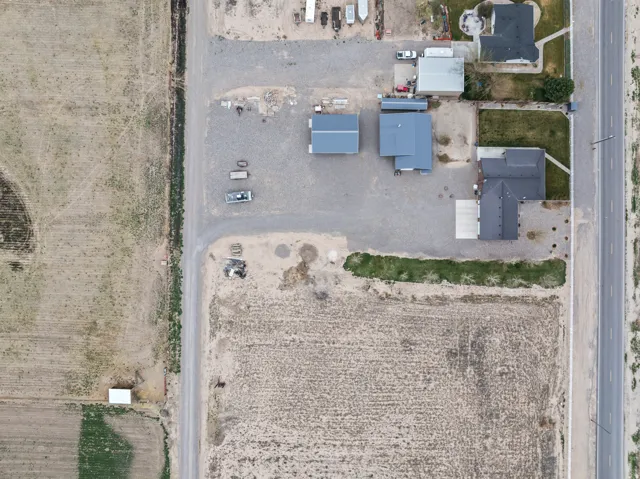 Aerial perspective showcasing multiple structures on a gravel lot, featuring three distinct buildings with dark gray roofing