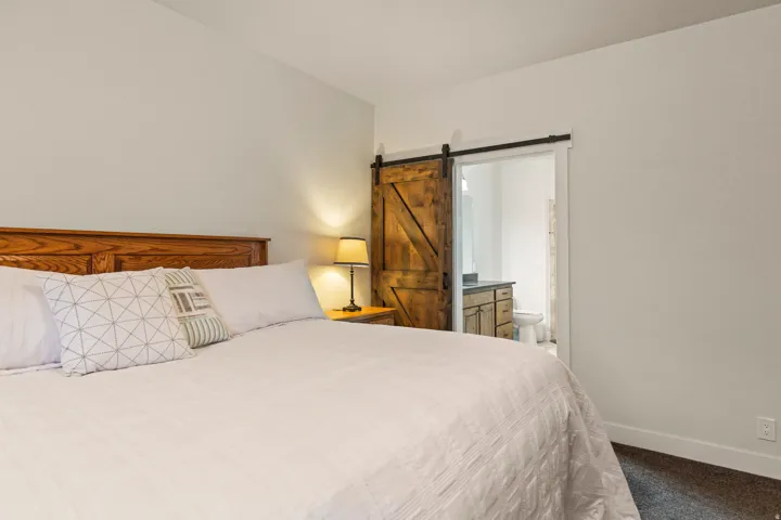 Bedroom featuring a barn door entry to a bathroom with a vanity and toilet