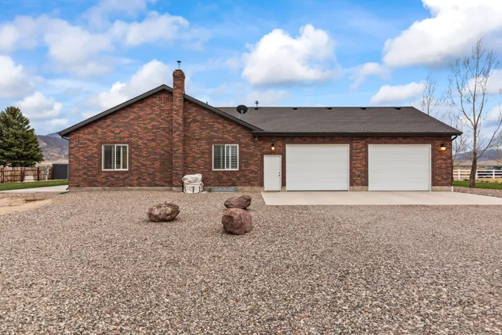 Red brick exterior featuring a multi-car garage with white doors, a white side access door, and exterior lighting fixtures