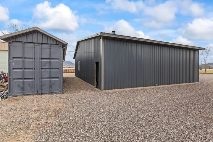 Two detached structures featuring corrugated metal siding and gravel ground cover