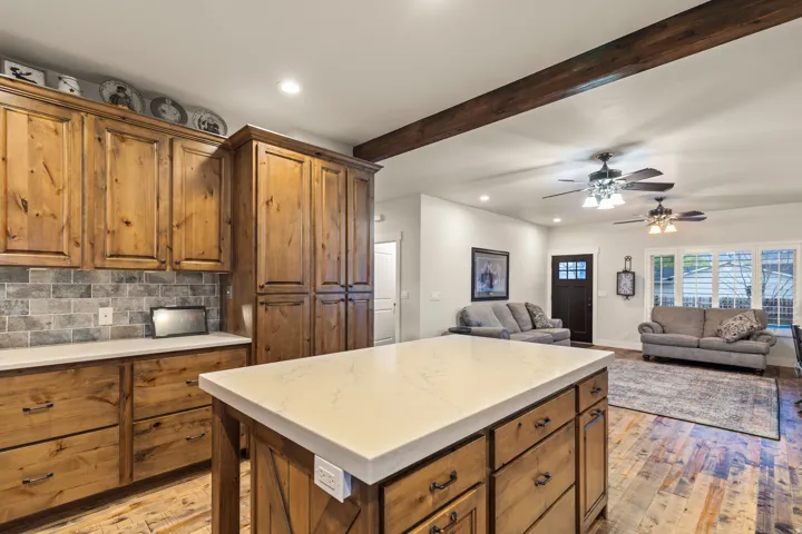 Kitchen island with a light-toned countertop, wood-finish cabinetry, and a subway tile backsplash