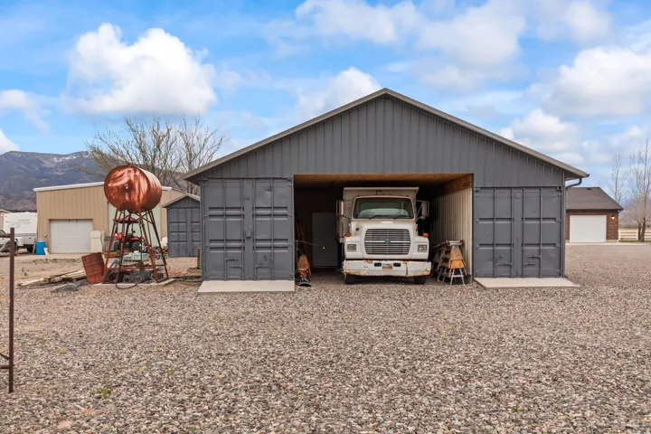 Metal-sided outbuilding with a large open bay and container-style doors