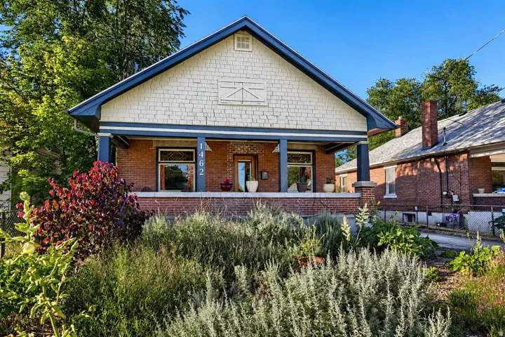 Brick-clad exterior featuring a covered porch, shake siding on the gable, and prominent house numbers