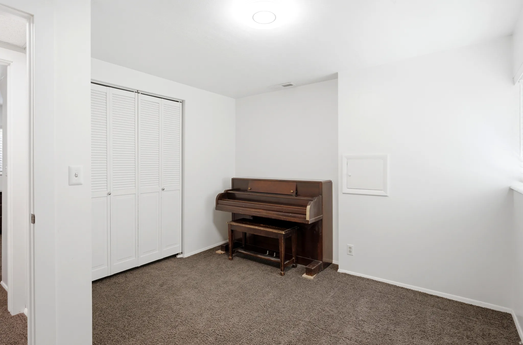 Carpeted room with white walls, louvered bi-fold closet doors, and recessed lighting