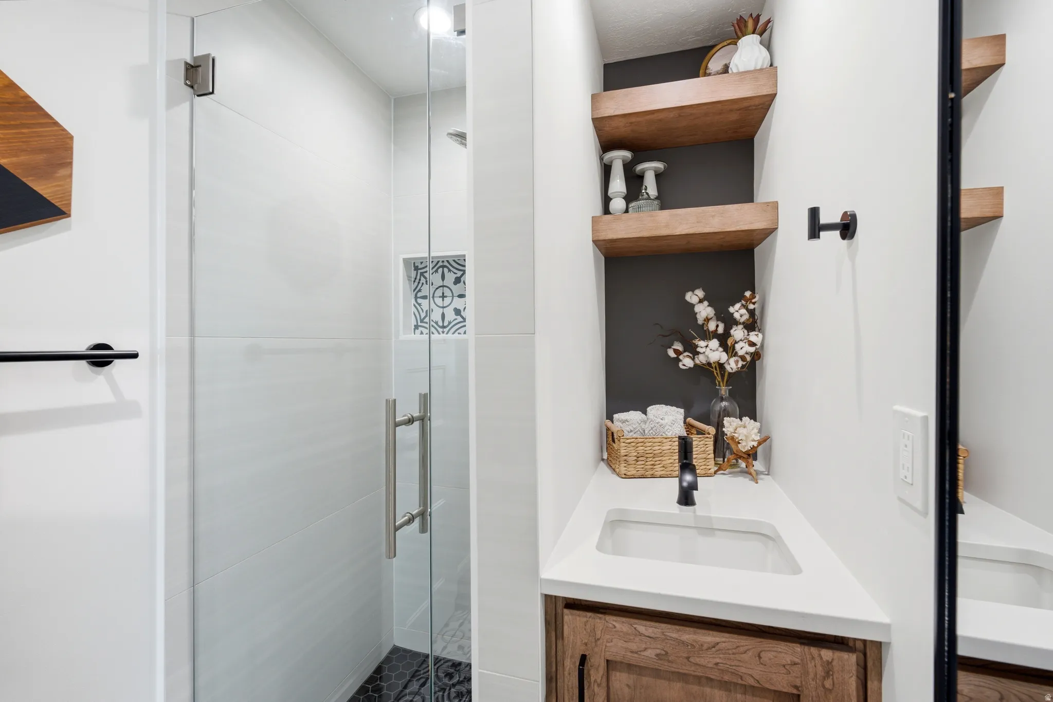 Modern bathroom featuring a glass-enclosed shower with white subway tile walls and a hexagonal black tile floor