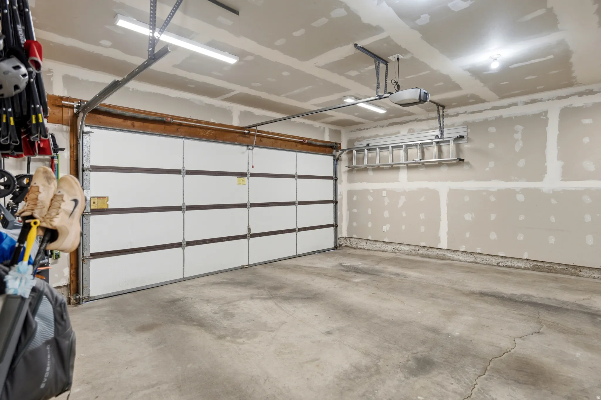 Spacious garage featuring a concrete floor, segmented overhead garage door, automatic opener, and overhead lighting