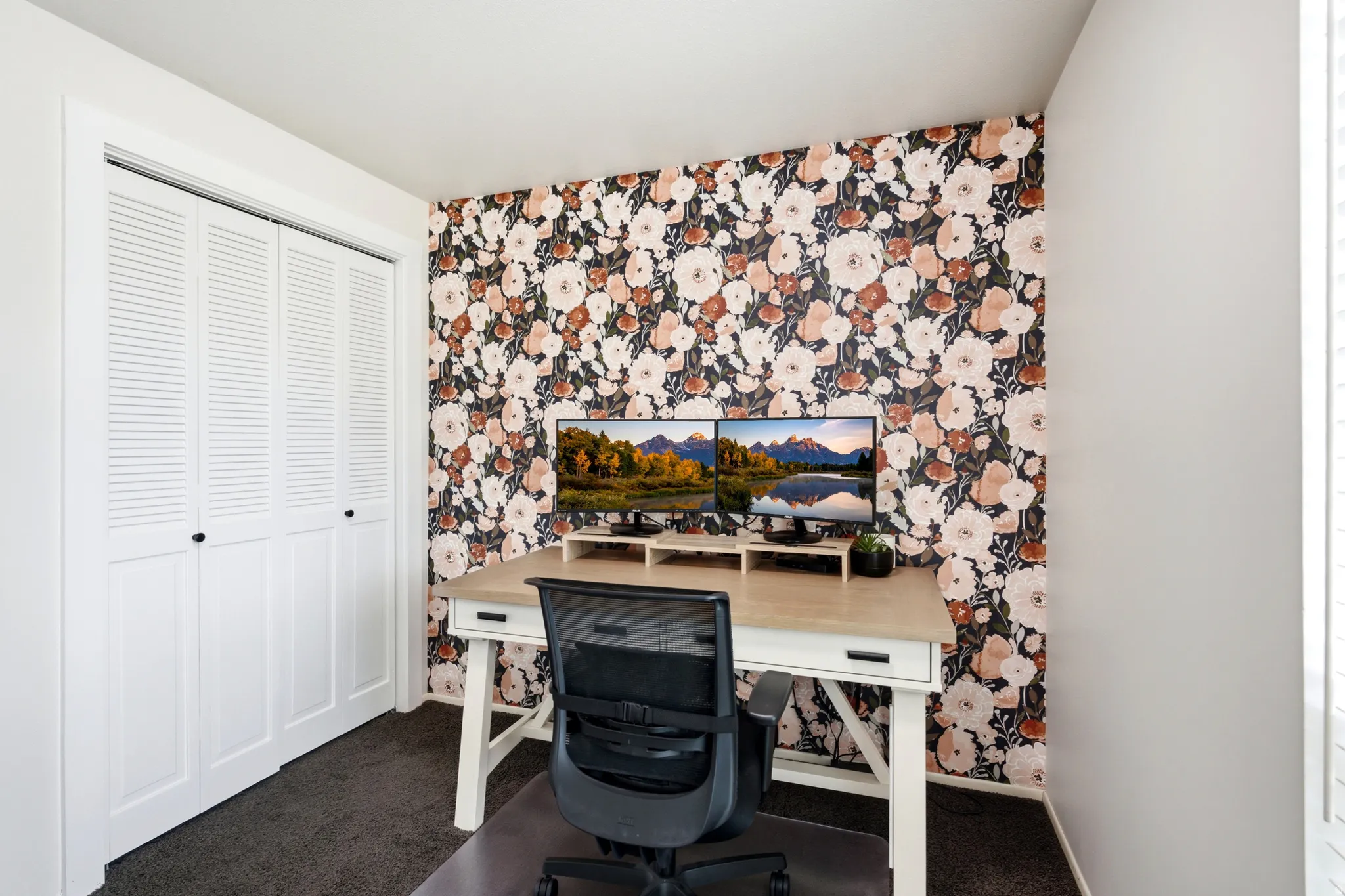 Accent wall with floral wallpaper, complemented by white walls, dark carpeting, and white louvered bi-fold closet doors