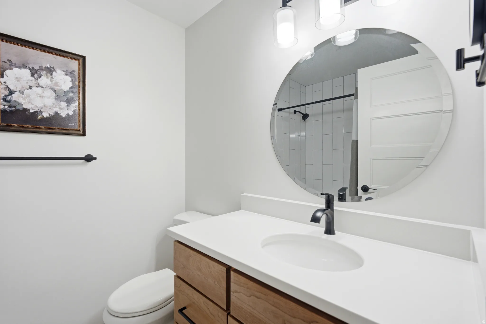 Bathroom featuring a wood-finish vanity with a white countertop, an undermount sink, and a matte black faucet