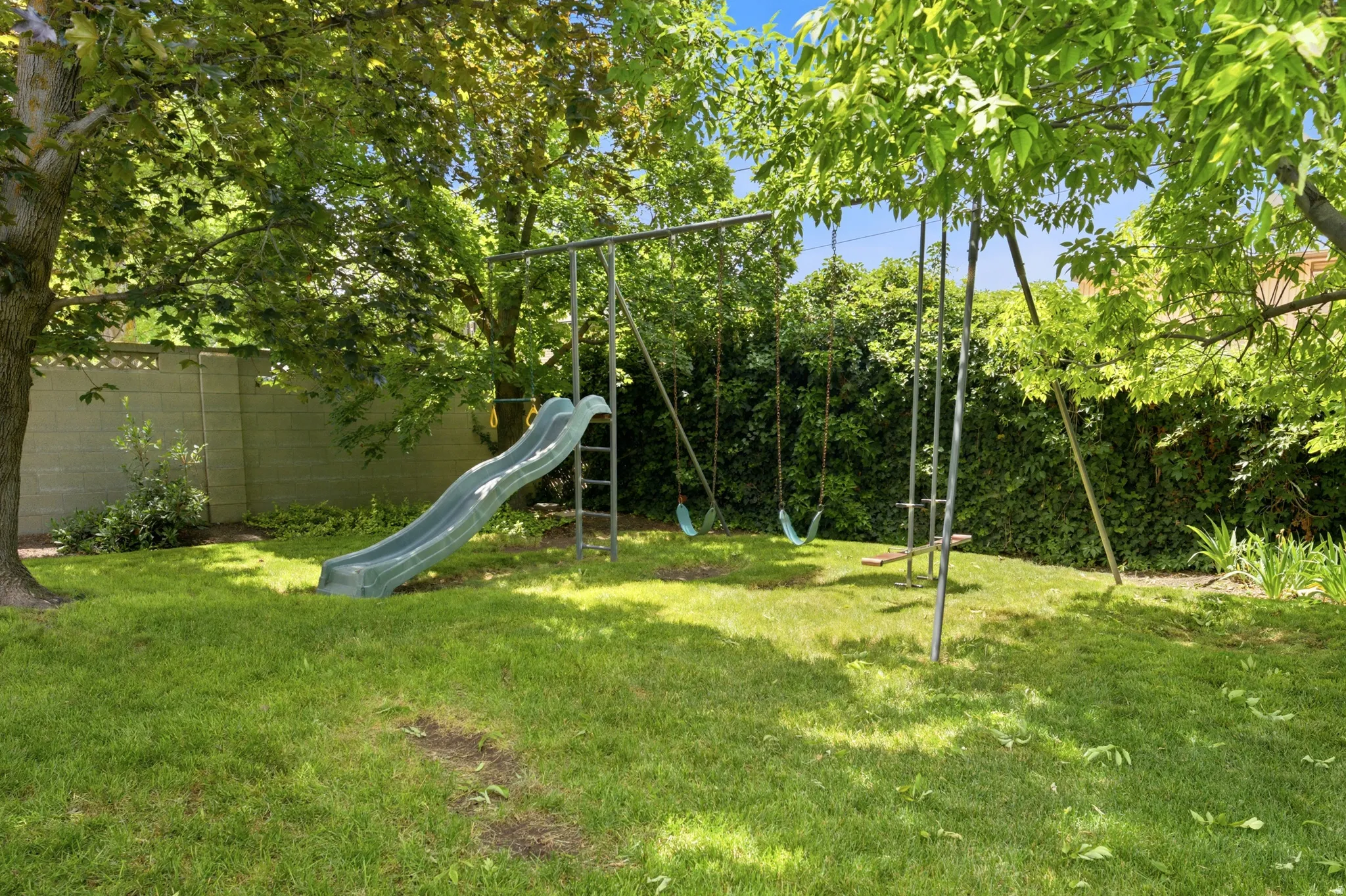 Spacious backyard featuring an established lawn and a mature tree providing natural shade