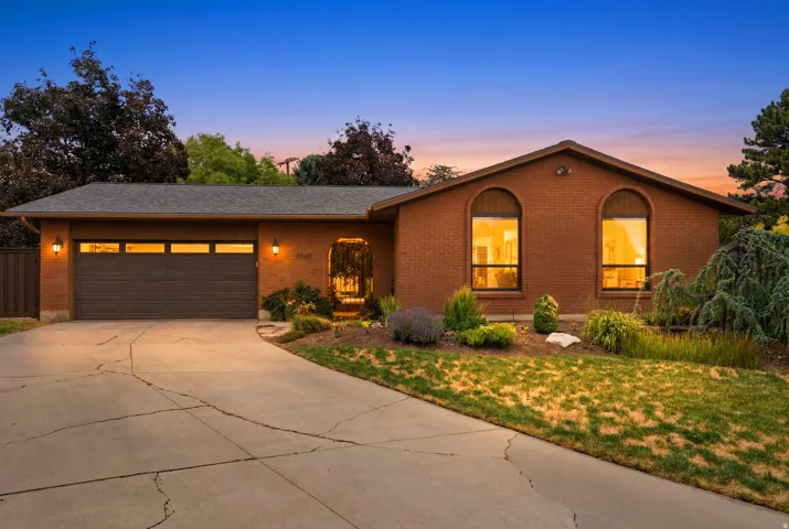 Brick exterior residence with a two-car garage, concrete driveway, and established front landscaping