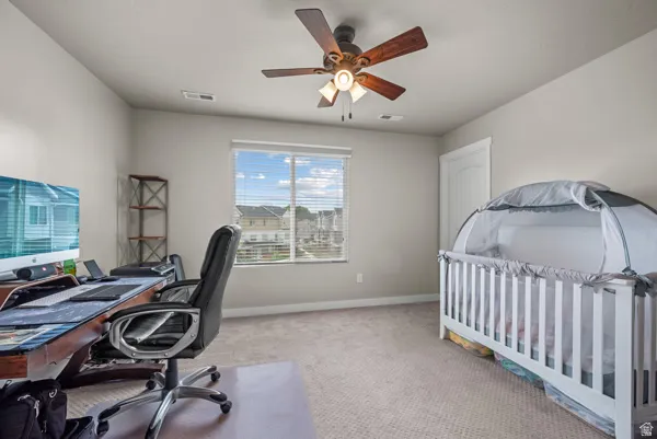 Carpeted room featuring a ceiling fan with light fixture, a window with blinds, and white trim